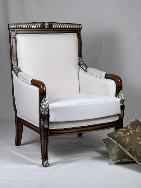Carved armchair with cream upholstery and silvered detail on the frame.