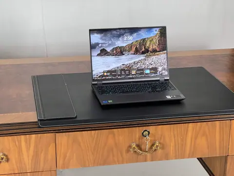 A laptop and a leather writing pad on the desk in use.