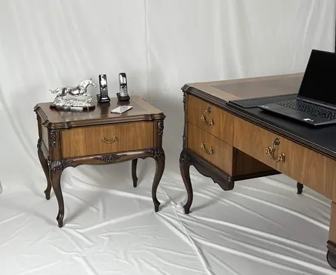 The side table with a telephone on top, desk behind.