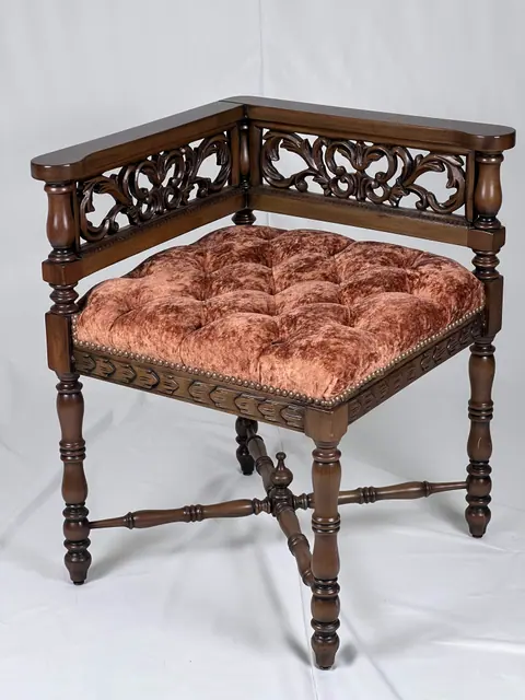 Corner seat with a pierced fretwork back and a tufted rust velvet cushion.