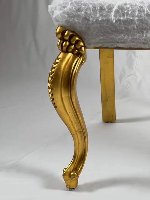 Front leg gilded and carved, with the seat still in its calico cover.