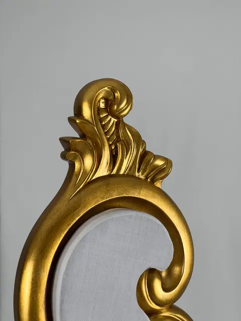 The top scroll of the back seen up close, gold leaf over the carving.