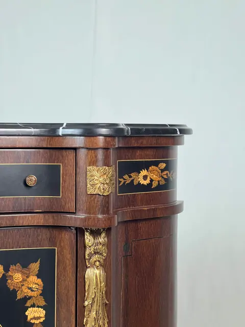 Close view of a gilt mount beside the marquetry panel.