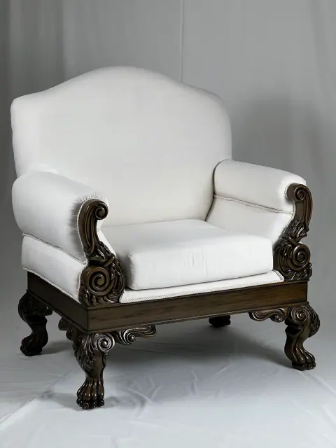 Deep armchair in white upholstery on a carved wooden base.