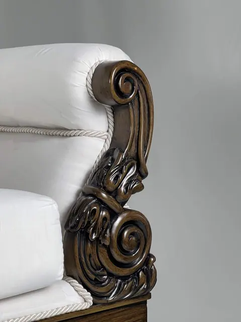 The carved arm, cut as a tight scroll with acanthus leaves.