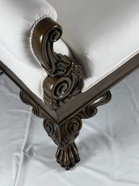 Corner of the frame where the scrolled arm meets the seat rail.