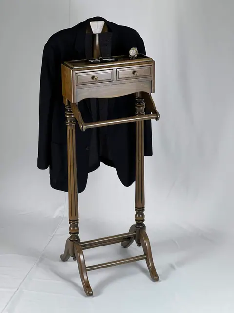The stand holding a navy jacket, with a tie over the rail.