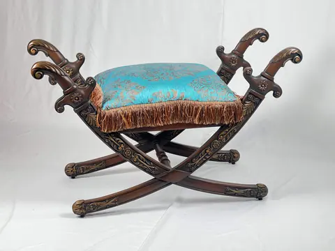 Side view of the stool, the carved arms curling outward.